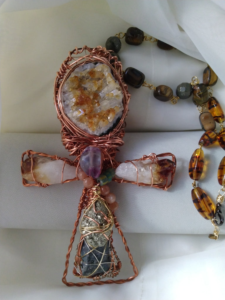Close up of handmade citrine druzy ankh necklace wire wrapped in artisan design